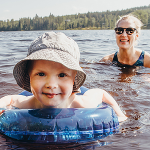 Lapsi uimarenkaassa ja nainen vedessä