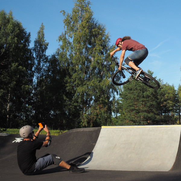 Kaksi nuorta temppuilee Pump Track radalla.
